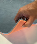 Hand holding a blue and orange acoustic underlay against a white background