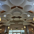 Ceiling with modern white acoustic panels and pendant lights in a room with large windows.