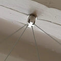 Metallic Pure-Kustik Ceiling Mount Suspending 4 Wires from a ceiling fixture on a wooden surface.