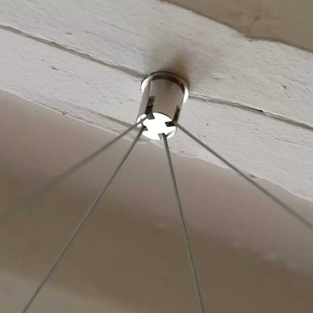 Metallic Pure-Kustik Ceiling Mount Suspending 4 Wires from a ceiling fixture on a wooden surface.