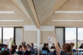 modern classroom with large windows, beige stone walls, and wooden ceiling beams, with Troldtekt Acoustic Panel|1200 x 600 x 25mm|Ultrafine K0, Natural Wood