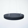 A black acoustic ceiling panel hanging by a metal wires and clips, against a background of a studio