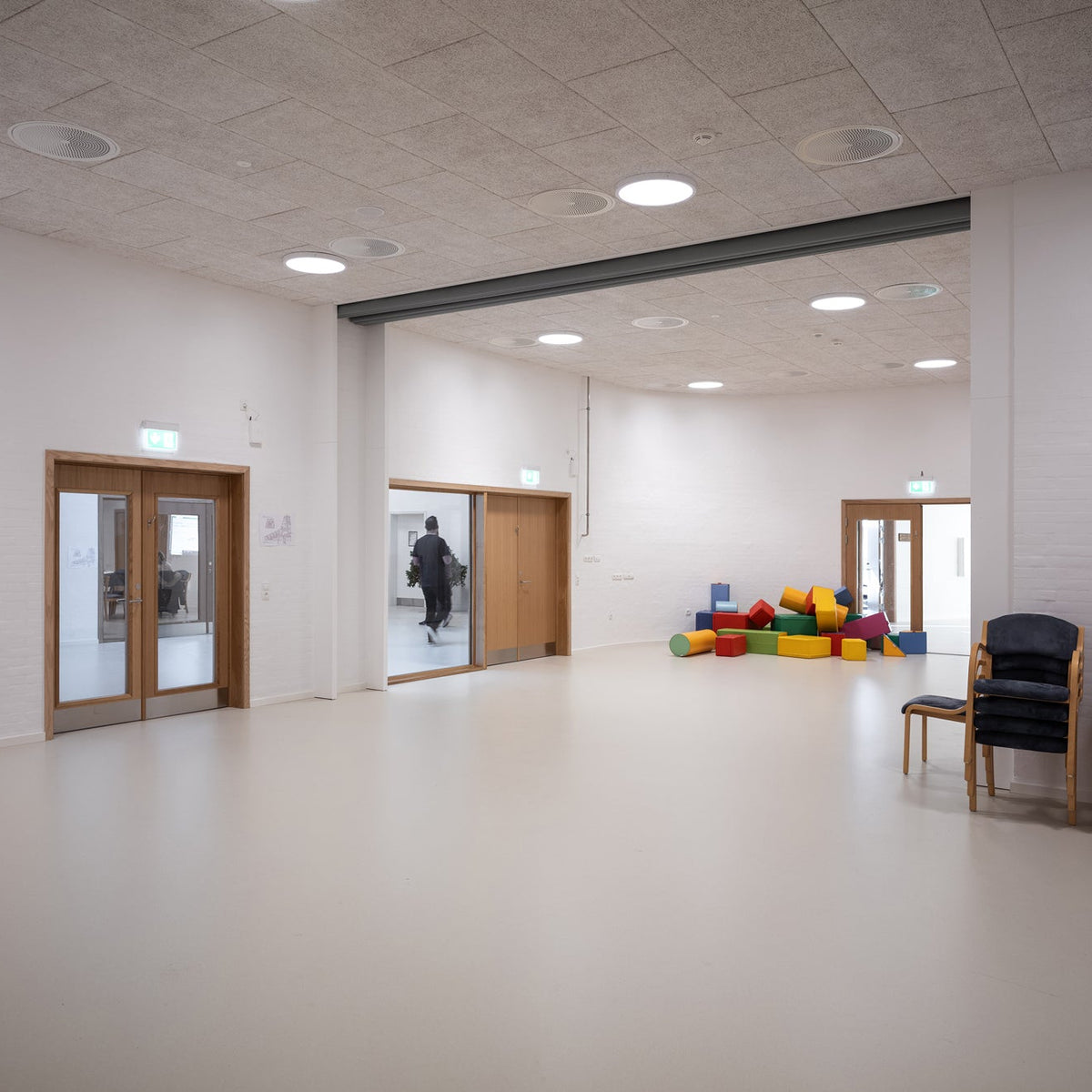 A large, bright indoor hall with white Trodtekt acoustic panels installed onto the ceiling to reduce echo and reverbiration.